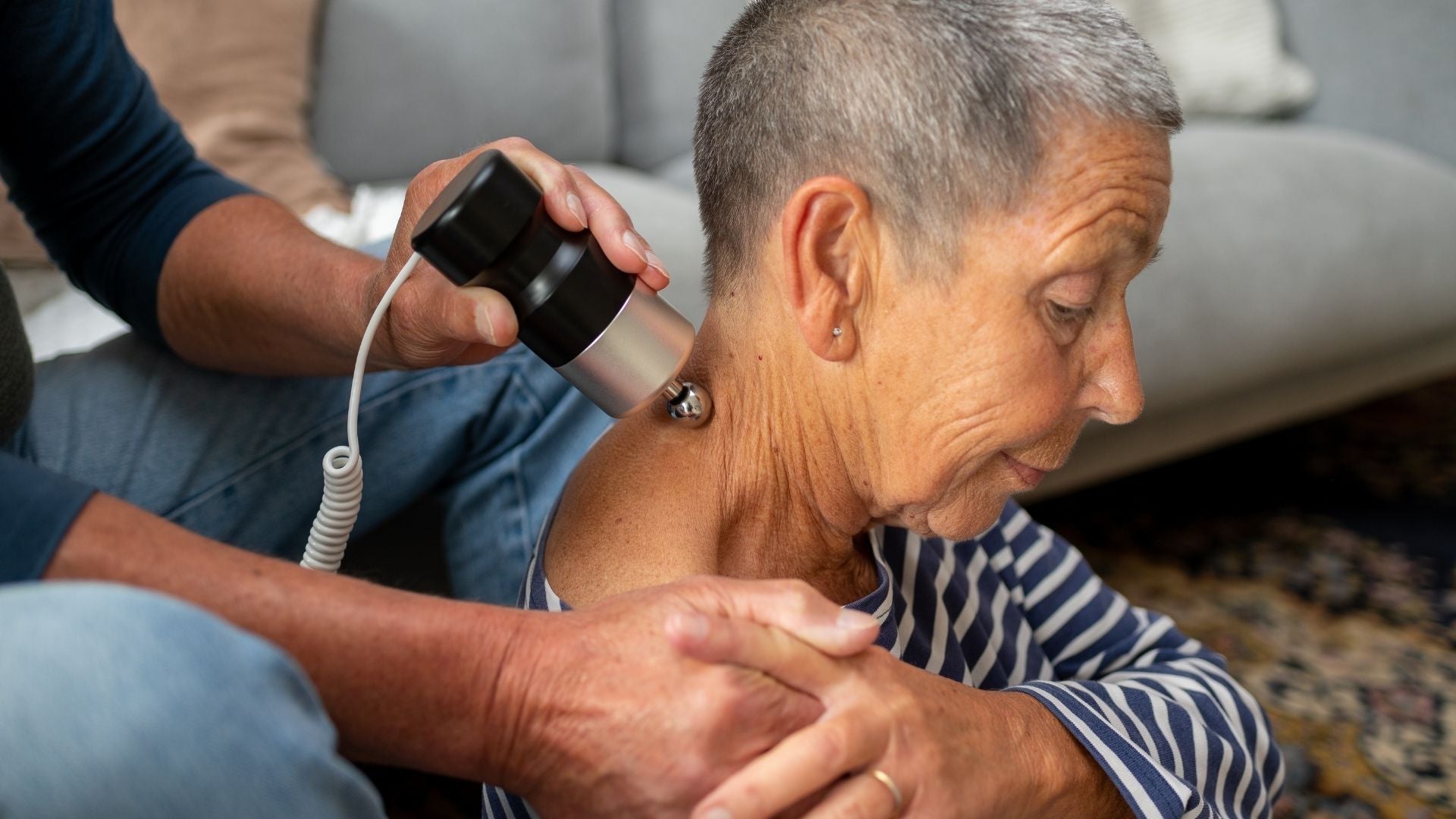Eine Frau erhält zuhause eine Schallmassage mit dem SoundWave Pro, während ihr Mann das Gerät zur Schallwellentherapie anwendet.