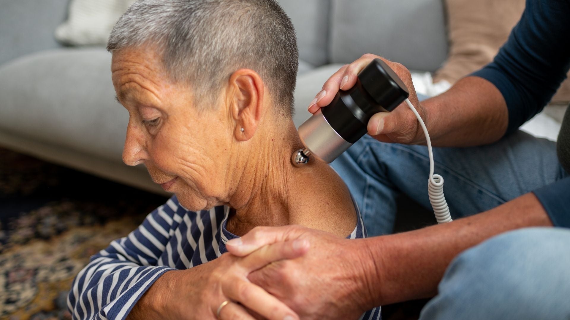 Eine Frau erhält zuhause eine Schallmassage mit dem SoundWave Pro, während ihr Mann das Gerät zur Schallwellentherapie anwendet.