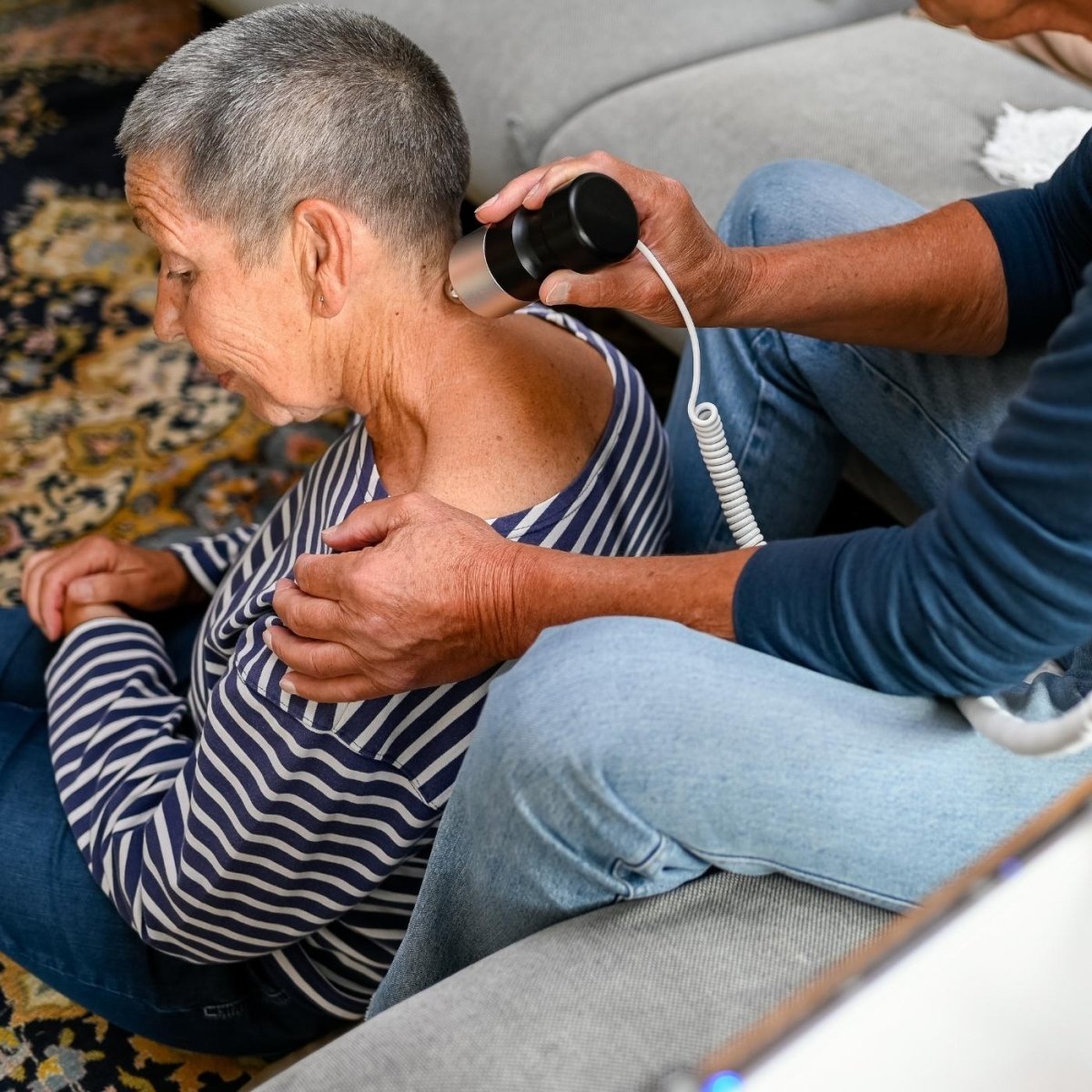 Eine Frau erhält zuhause eine Schallmassage mit dem SoundWave Pro, während ihr Mann das Gerät zur Schallwellentherapie anwendet.